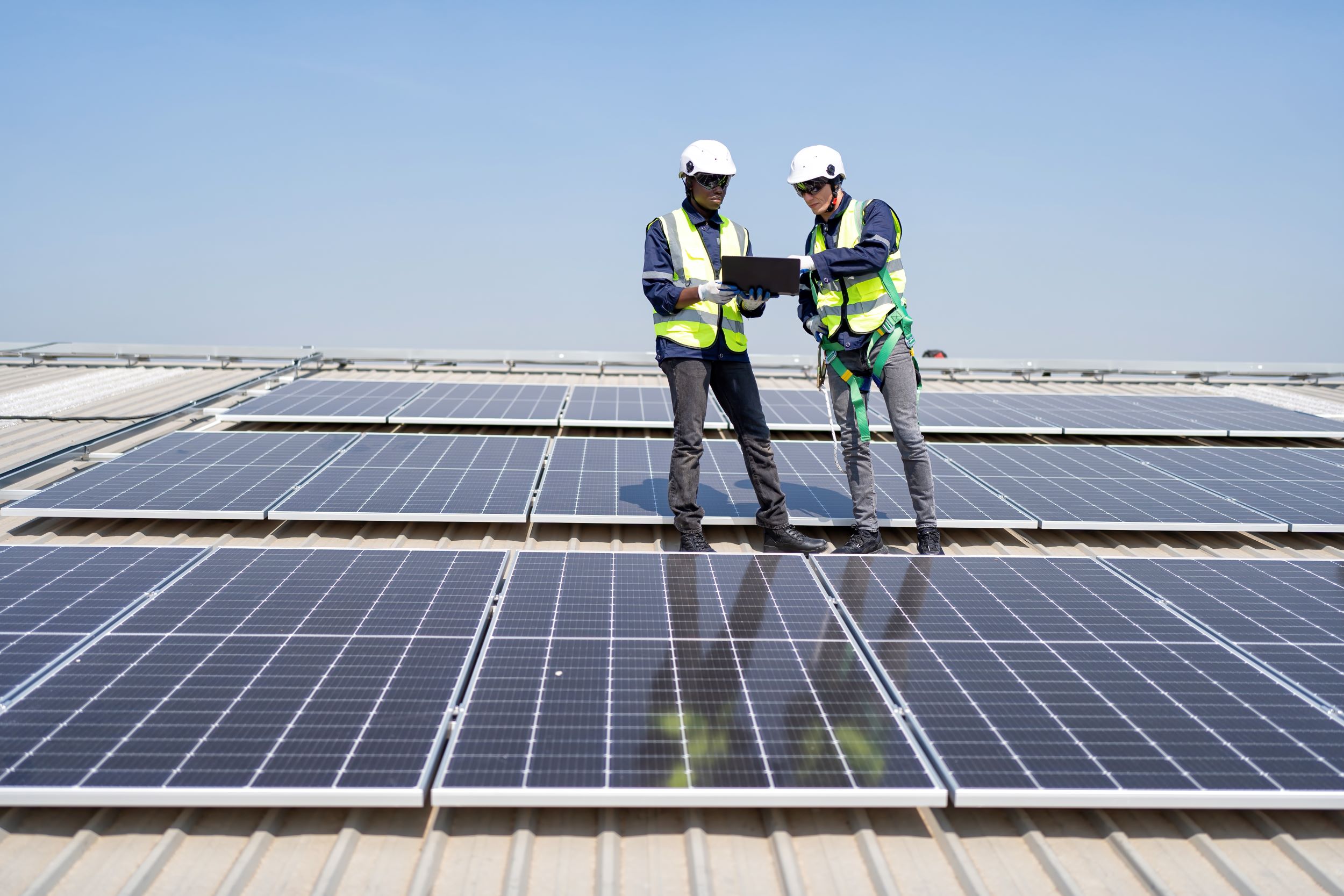 Twee engineers staan bij zonnepanelen en kijken naar een tablet