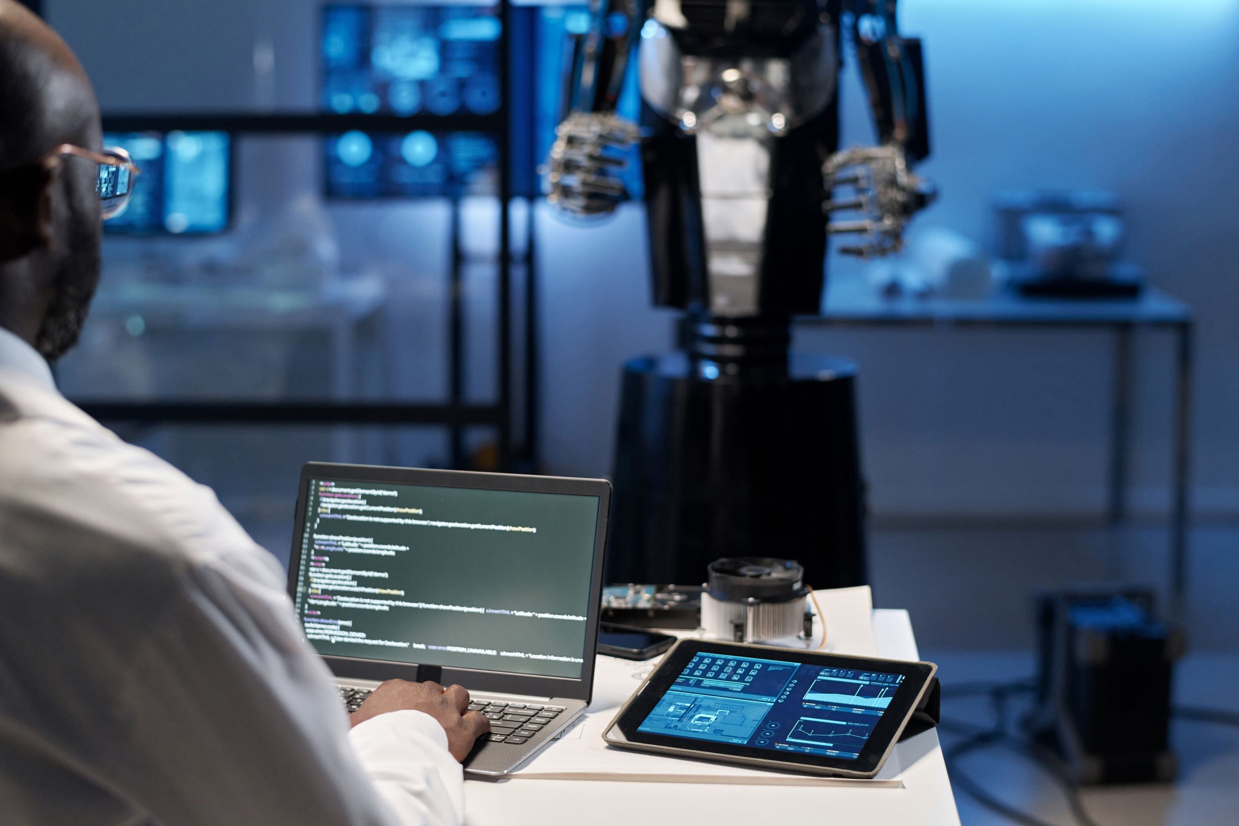 Een robot en een man die codes op een laptop typt