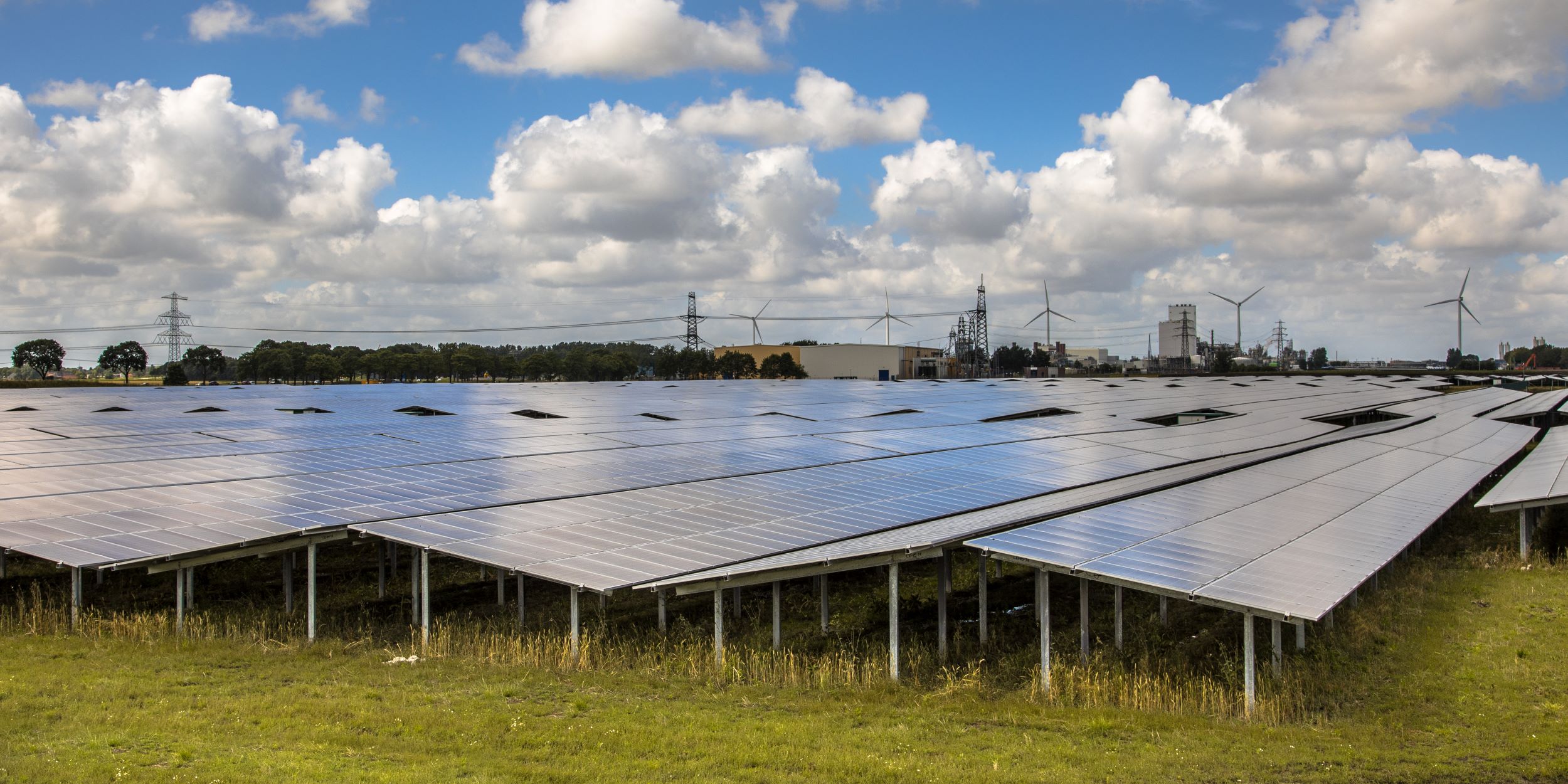 Veld met zonnepanelen met op de achtergrond windmolens