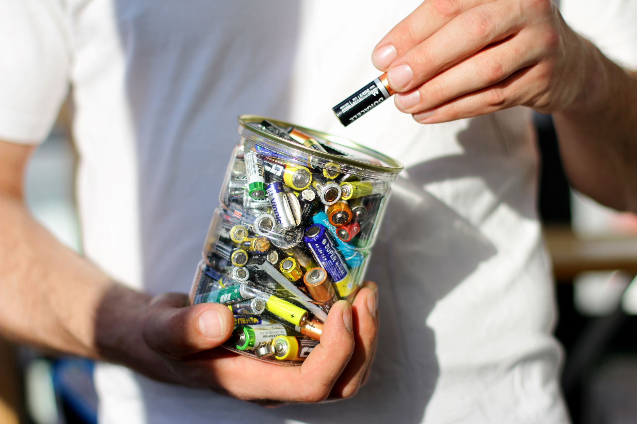 Hand van iemand die een batterij in een pot met batterijen doet