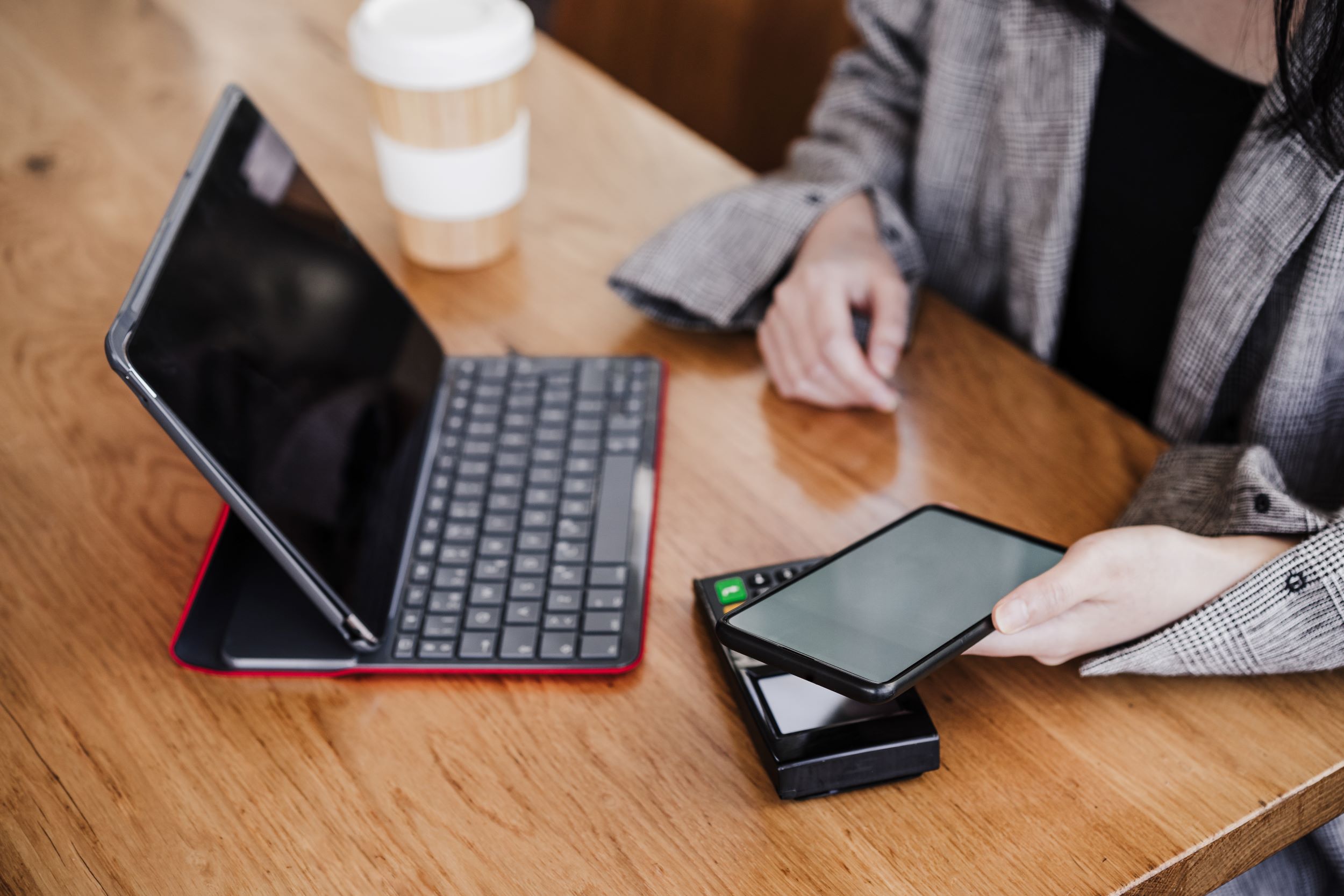 Vrouw zit aan een tafel met een tablet en telefoon